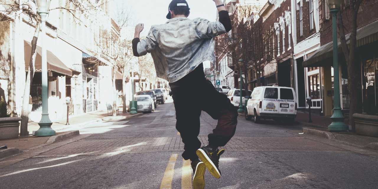 Mand er glad og hopper på en gade