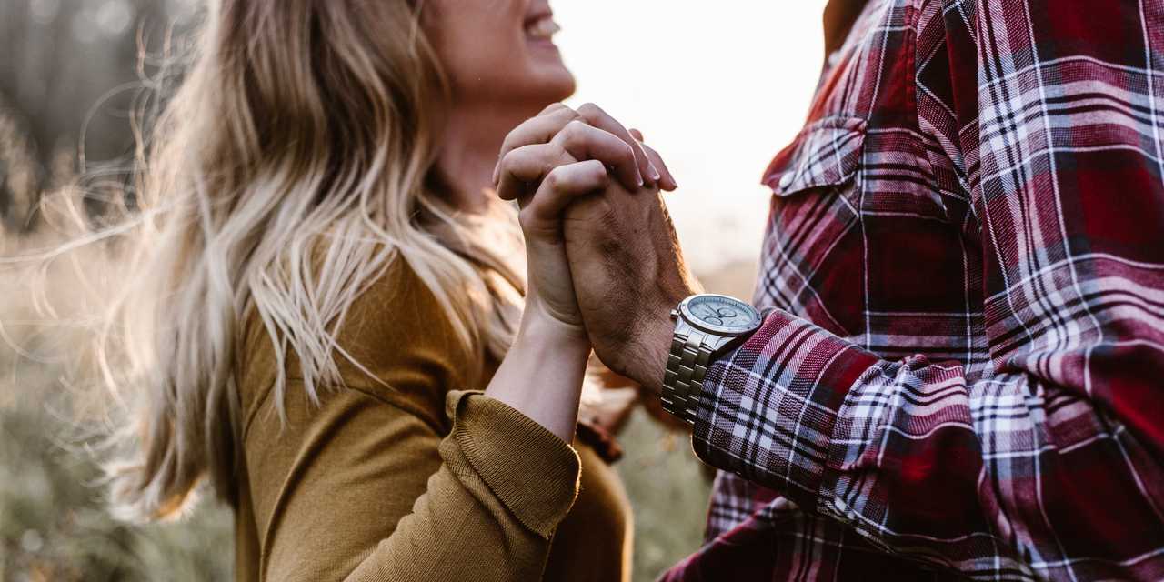 Pariskunta pitää käsistä kiinni pellolla