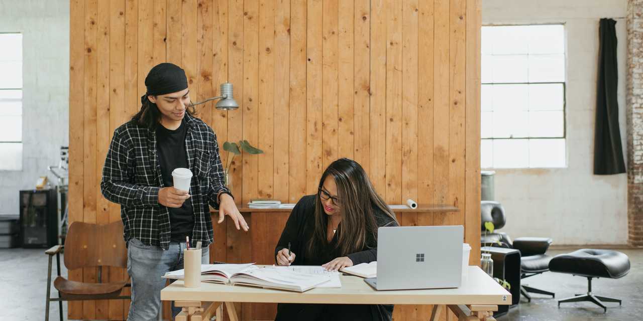 Kvinna skriver och man stannar med kaffe