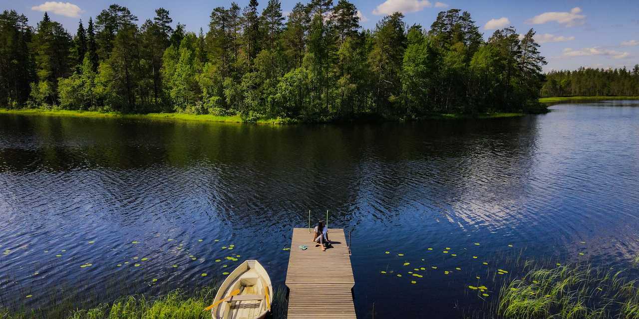 Laituri ja soutuvene vehreän järven rannassa