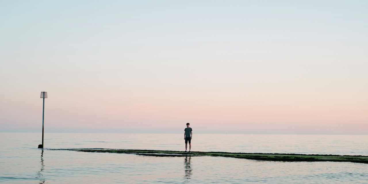 Ihminen seisoo laiturilla ja katsoo horisonttia