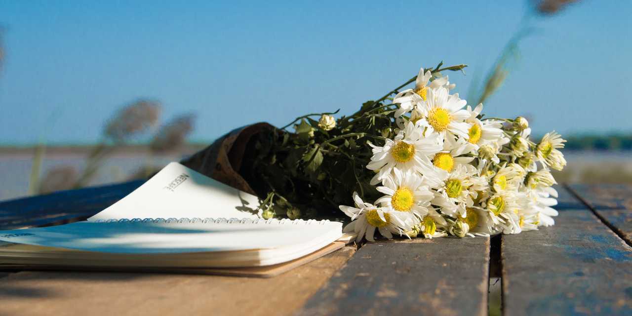 Block med papper och en bukett med vita blommor