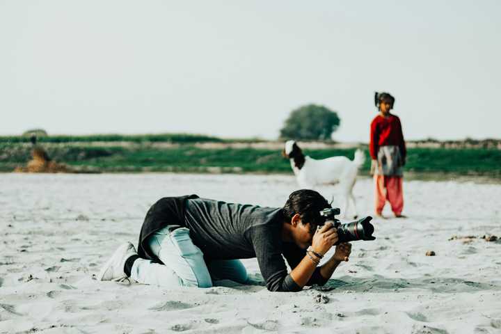 A person lying on sand and taking a picture