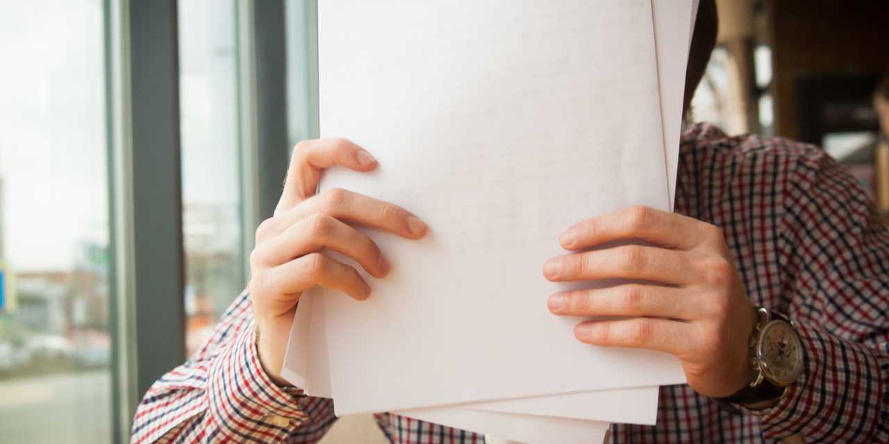 Mies pitämässä papereita kädessään