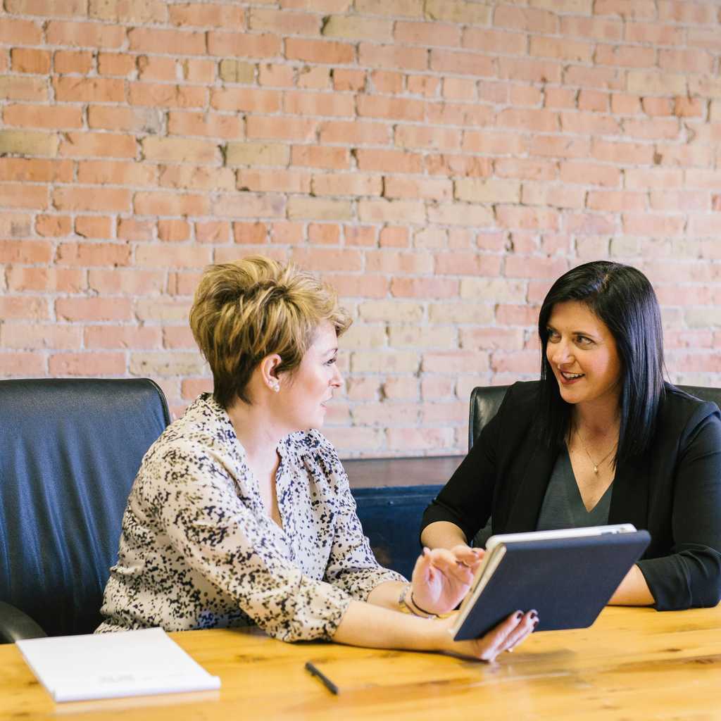 Two women discussing in a meeting about notes