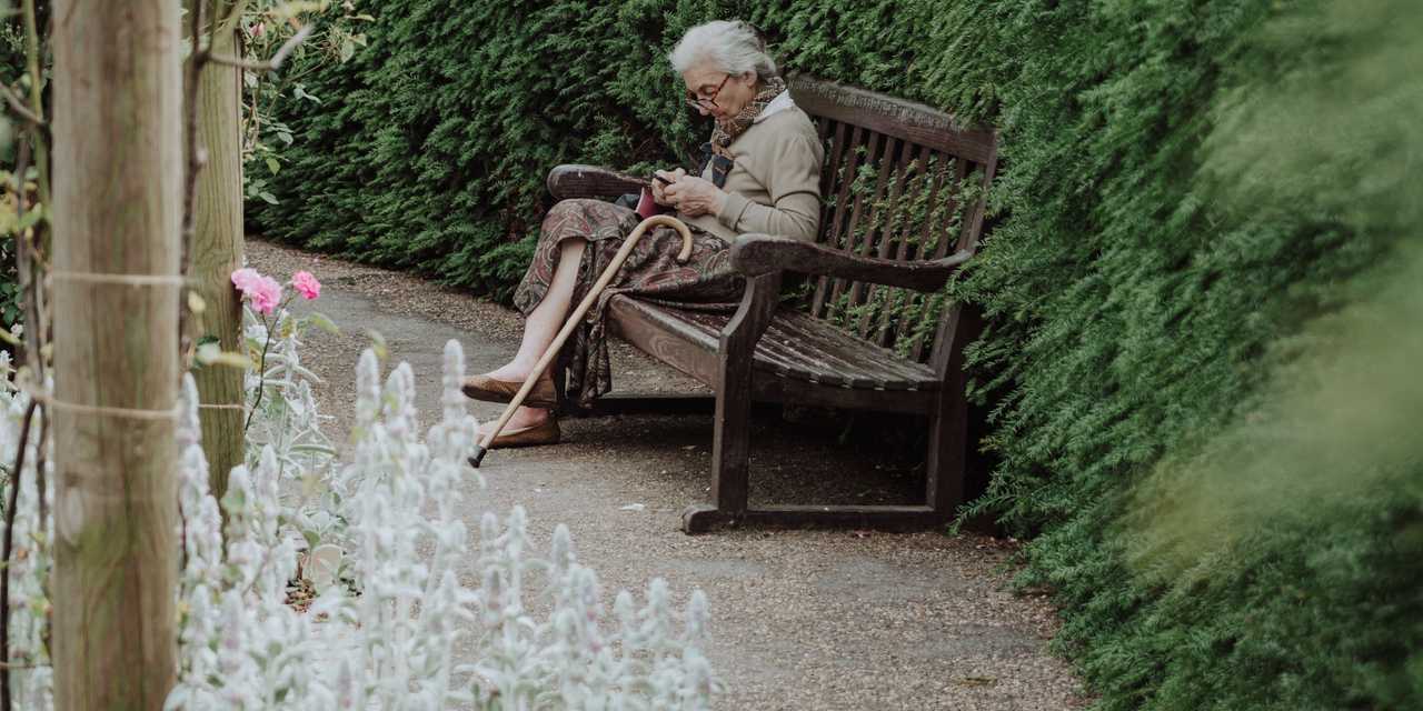 vanhempi henkilö istumassa puistonpenkillä.