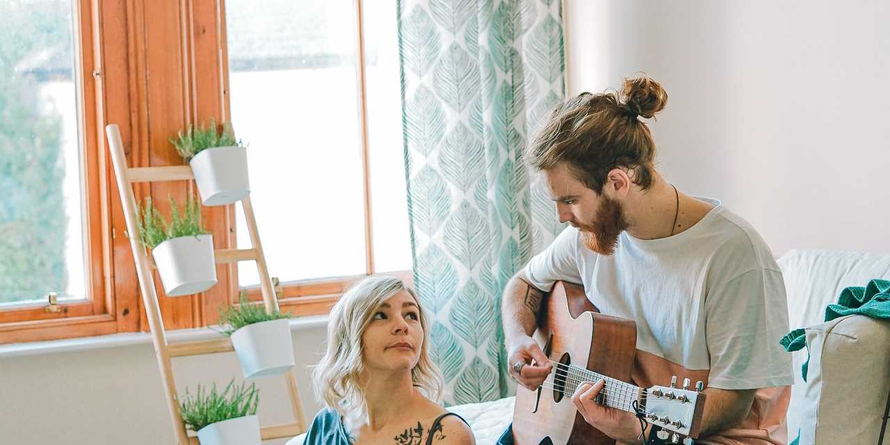 To personer i rummet. Den anden spiller guitar.