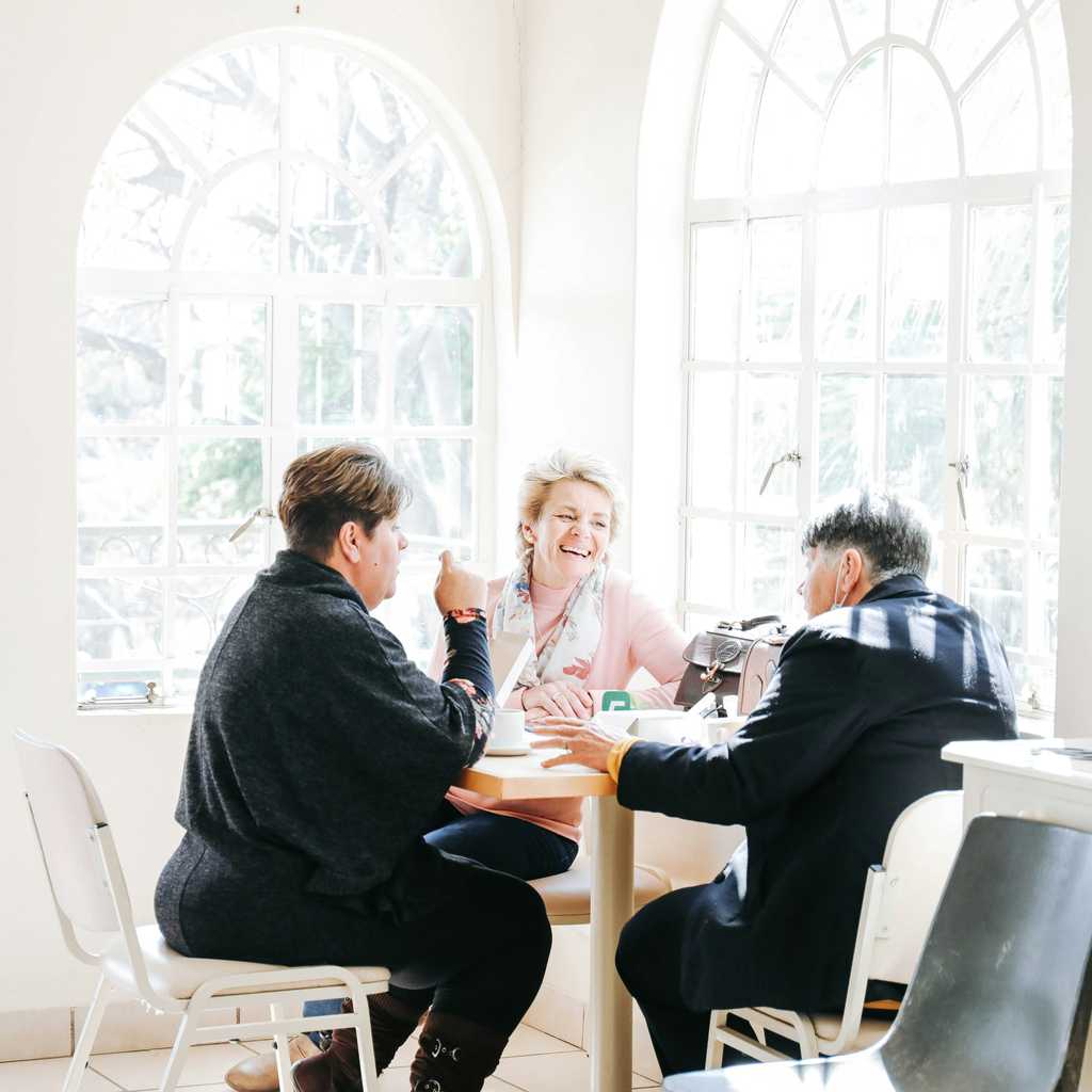 Kolme aikuista istuu ruokapöydän ääressä