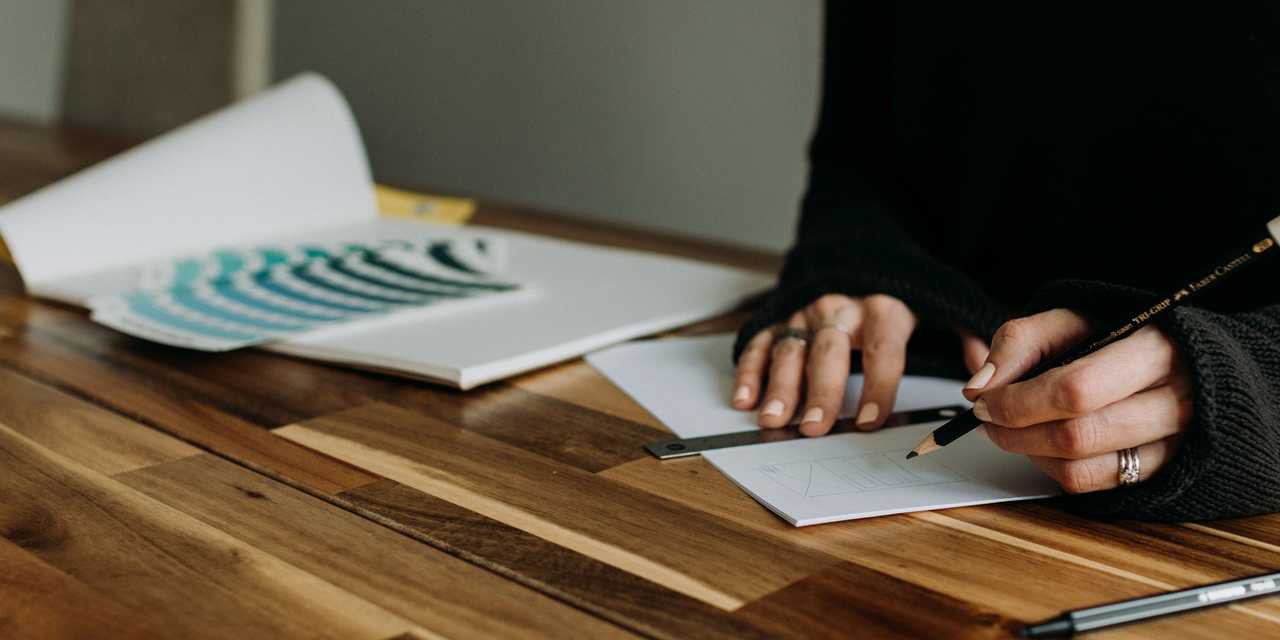 Henkilö kirjoittaa lyijykynällä paperille. 