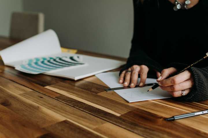 Henkilö kirjoittaa lyijykynällä paperille. 