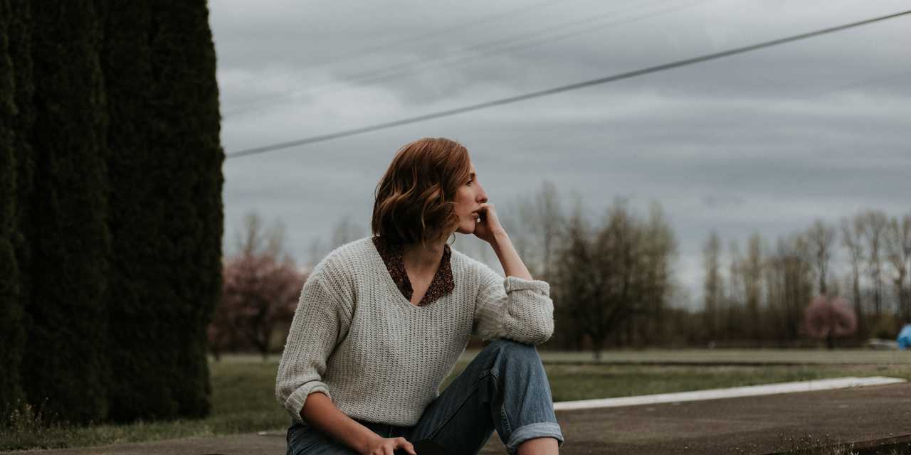 Nainen istuu pihamaalla kirjan kanssa