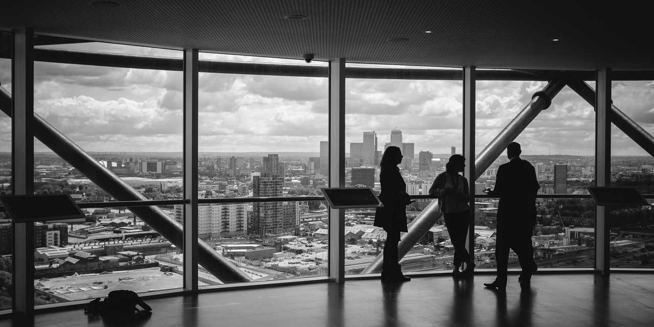 kolme henkilöä toimistossa. Kaupunkimaisema taustalla. 