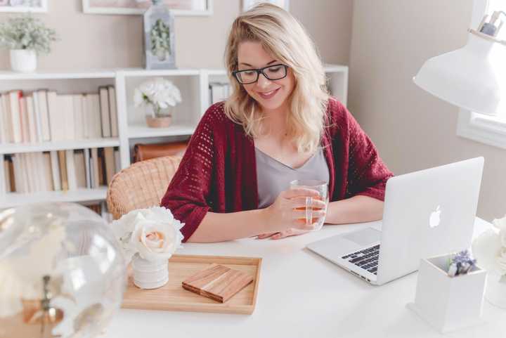 A Woman drinking tea and sitting in front of a laptop